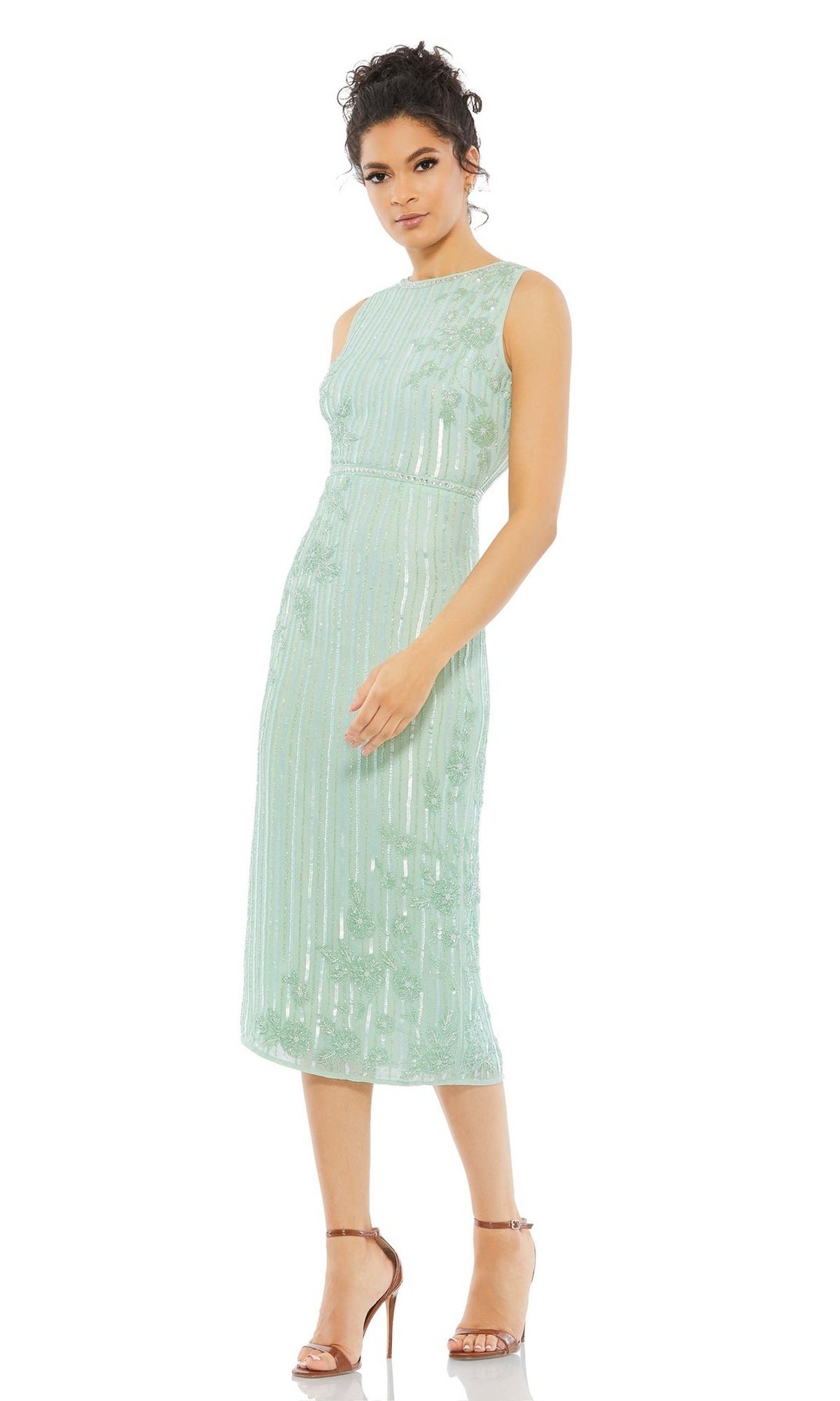 A woman wearing the Beaded Midi Wedding Guest Dress: Mac Duggal 70260, a sleeveless, light green floral tea-length dress, with strappy high-heeled sandals, stands against a white background.